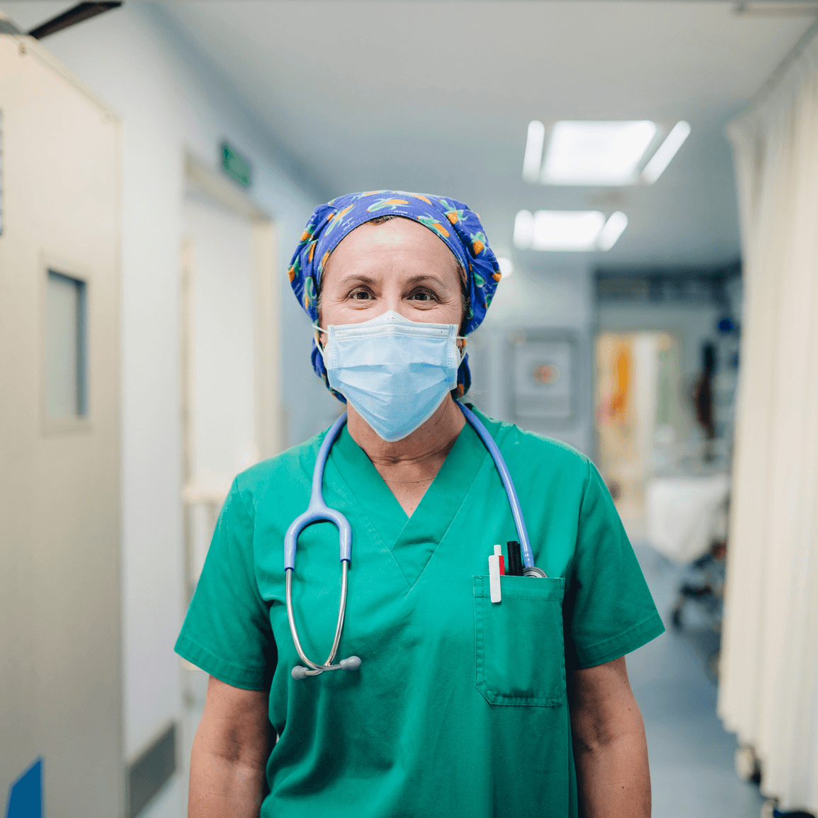 Nurse in scrubs and mask in a hospital corridor